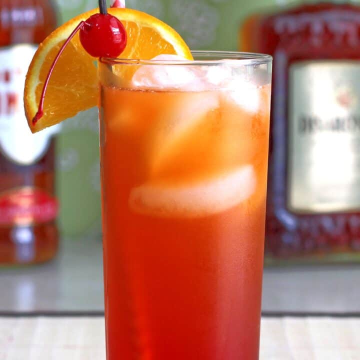 Alabama Slammer drink on table in front of liquor bottles