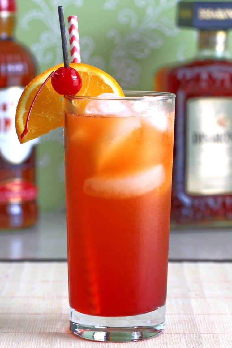 Alabama Slammer drink on table in front of liquor bottles