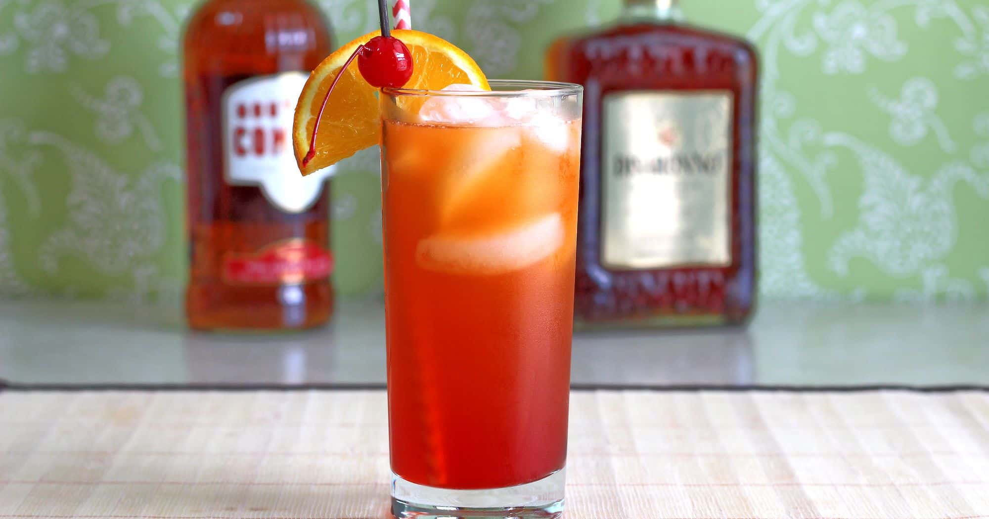 Alabama Slammer drink on table in front of liquor bottles