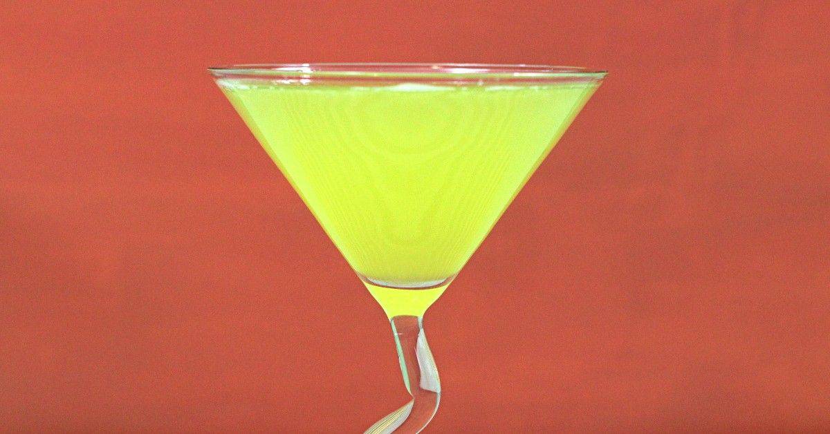 Bright yellow Algonquin Cocktail in front of dark orange background