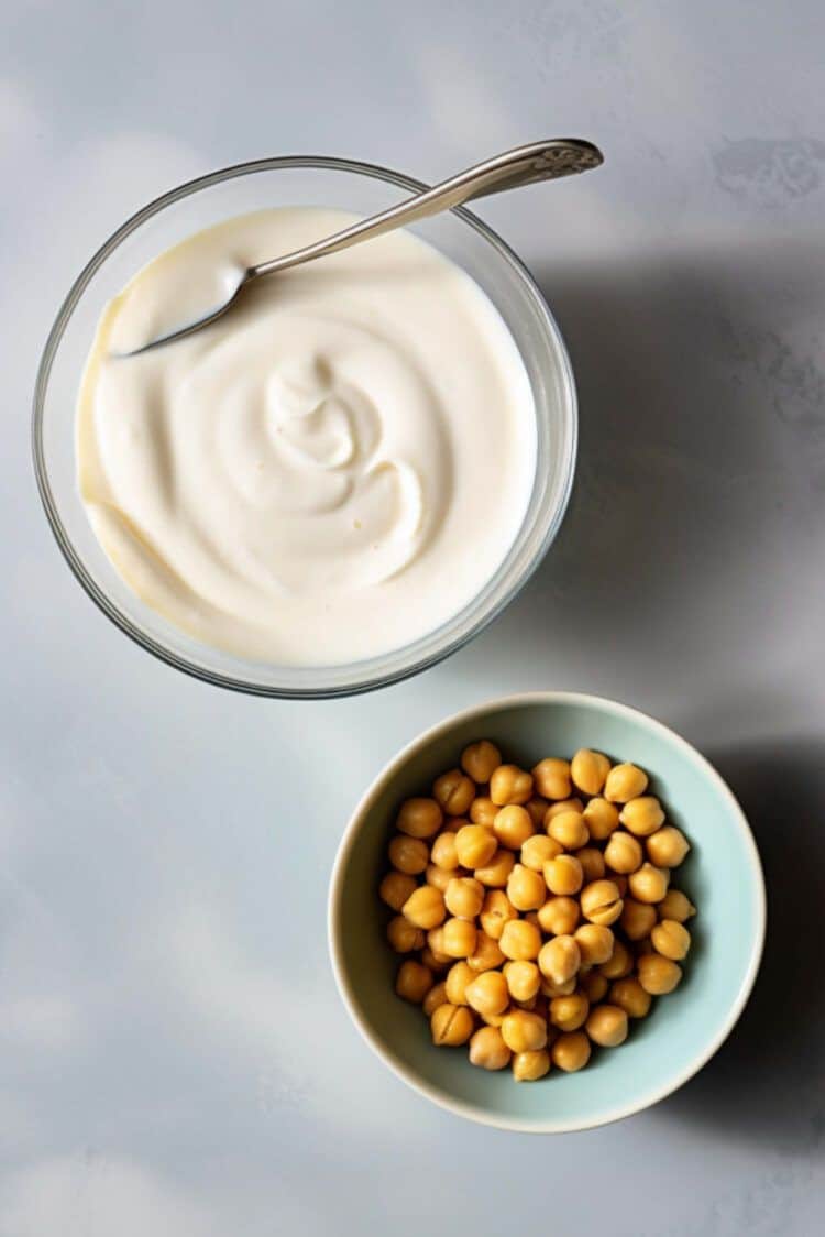 Aquafaba whipped in bowl next to bowl of chickpeas