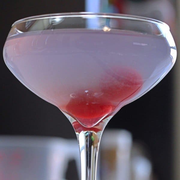 Closeup of Aviation cocktail with cherries fallen to bottom of glass