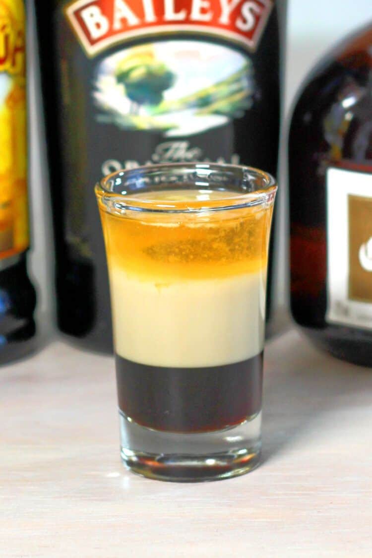 B52 shot on table in front of liquor bottles