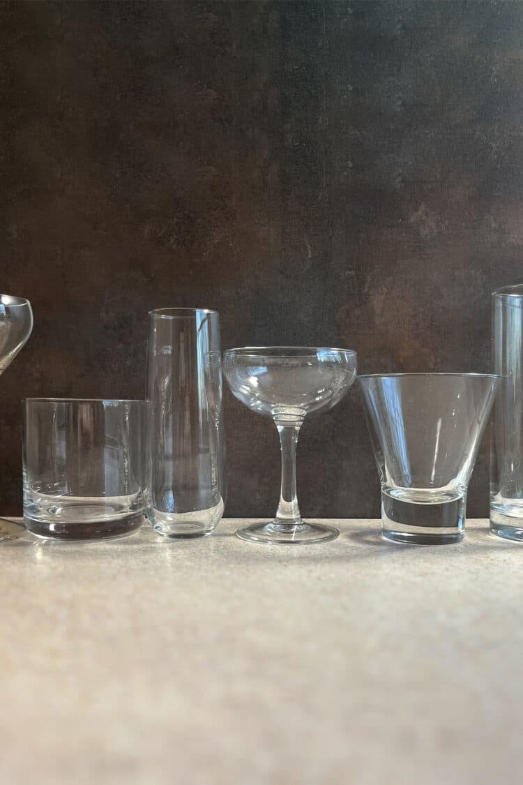 Several bar glasses lined up against dark background