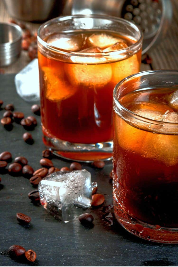 Black Russian drinks on table with coffee beans and ice cubes