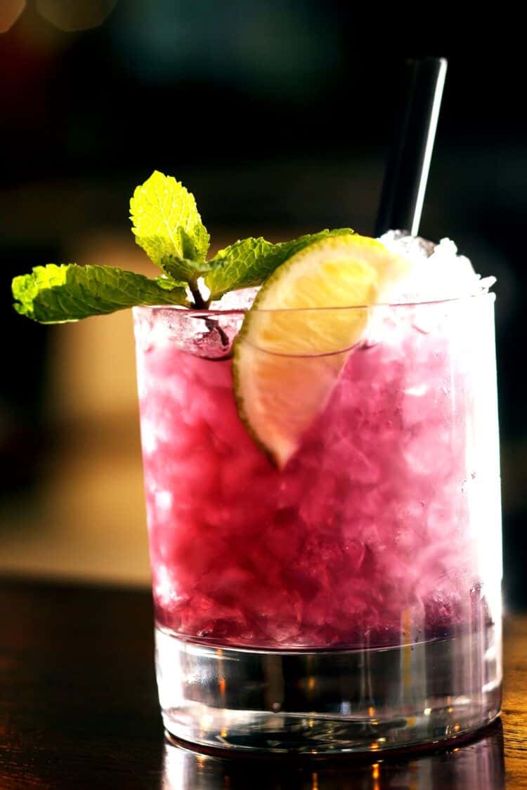 Blue Nectar Blackberry Bramble cocktail on bar with mint garnish