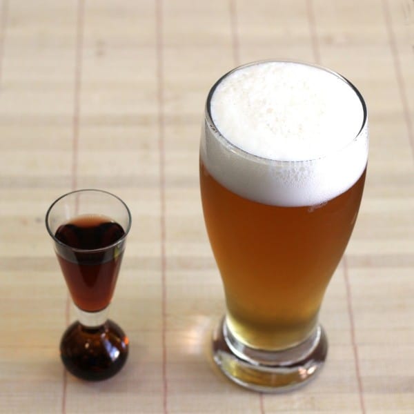 Glass of beer next to shot of whiskey on placemat