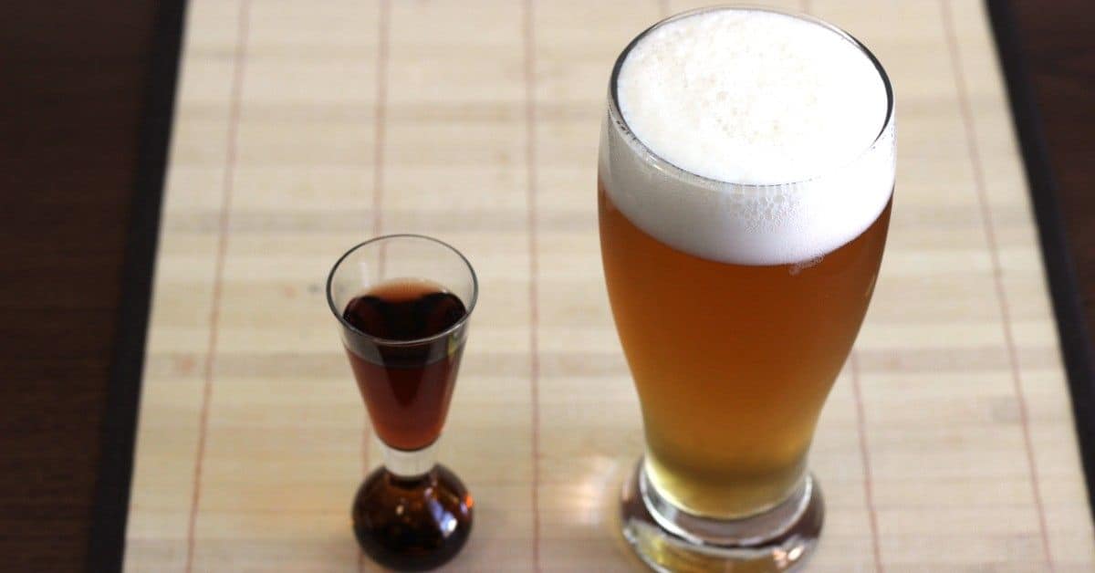 Boilermaker beer in Pilsner glass next to shot of whiskey