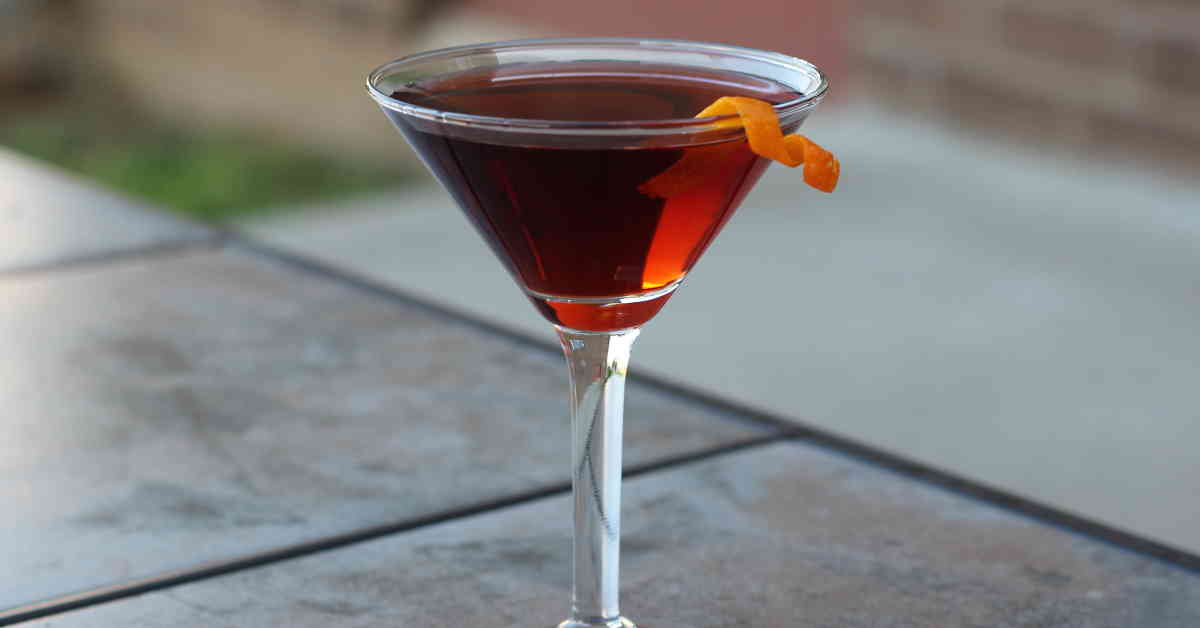 Boulevardier drink with orange twist on patio table