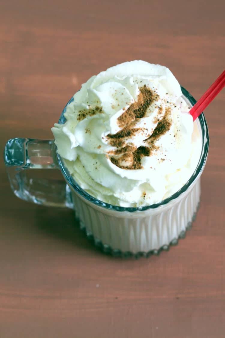 Butterscotch Coffee Cocktail in front of bottles of liquor and whipped cream