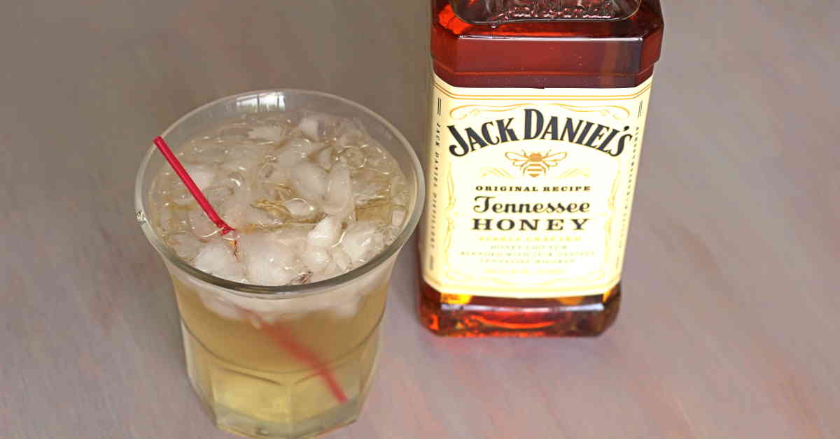 Overhead view of Club Honey cocktail on table next to bottle of Jack Daniel's honey