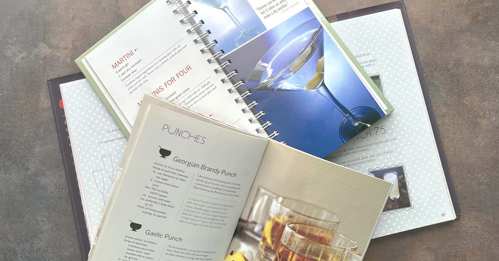 Cocktail recipe books piled on table