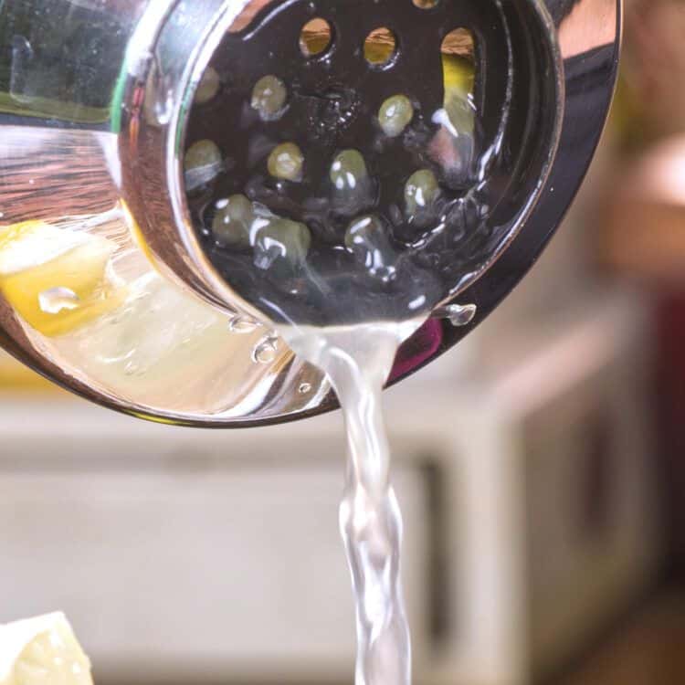 Straining margarita into glass