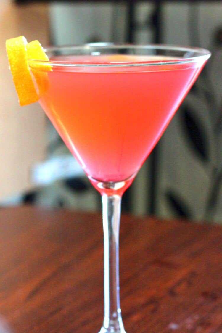 Cosmopolitan cocktail with lemon twist against blurry background