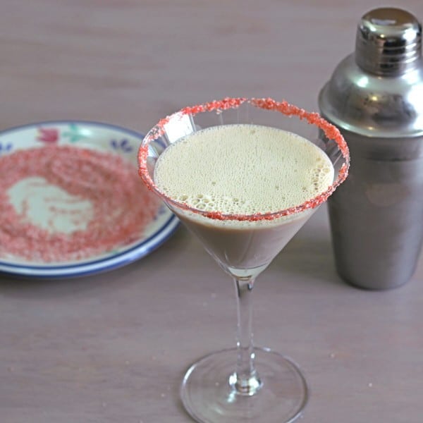 Creamy Chocolate Raspberry cocktail in front of saucer with red sugar and shaker