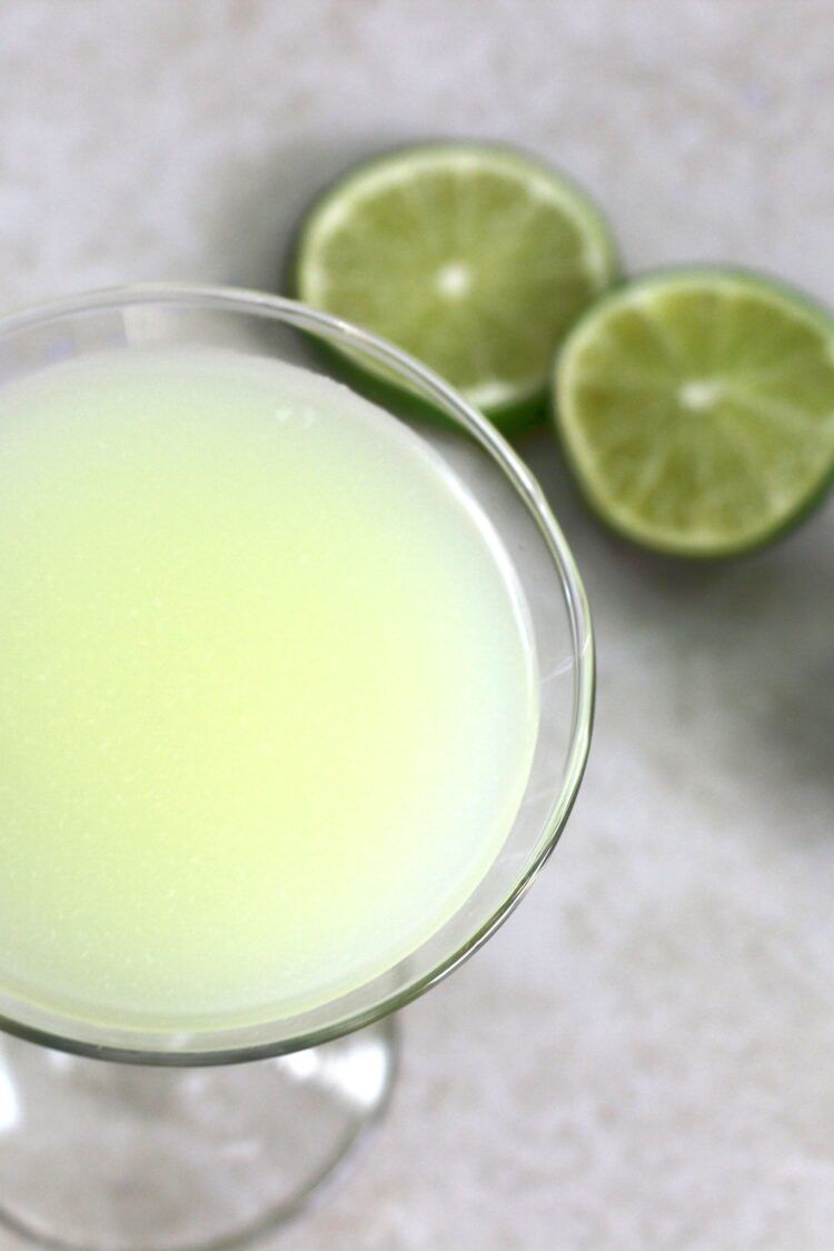 Overhead view of Daiquiri cocktail with lime wedges on table