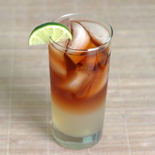 Closeup view of Dark 'n' Stormy cocktail with lime wedge on placemat