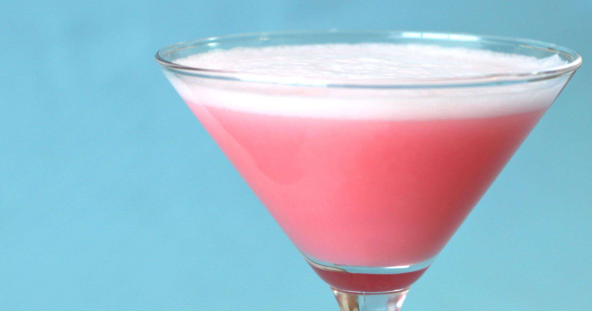 Closeup of Pink Easter cocktail against blue backdrop