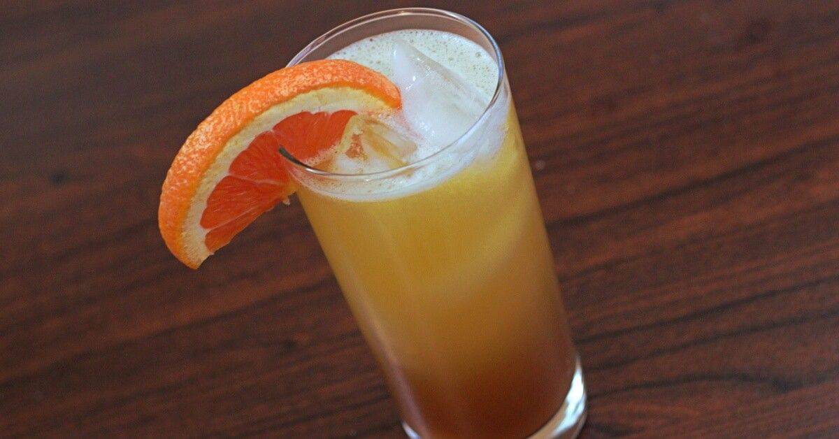 Executive Sunrise cocktail in tall glass with ice and orange slice