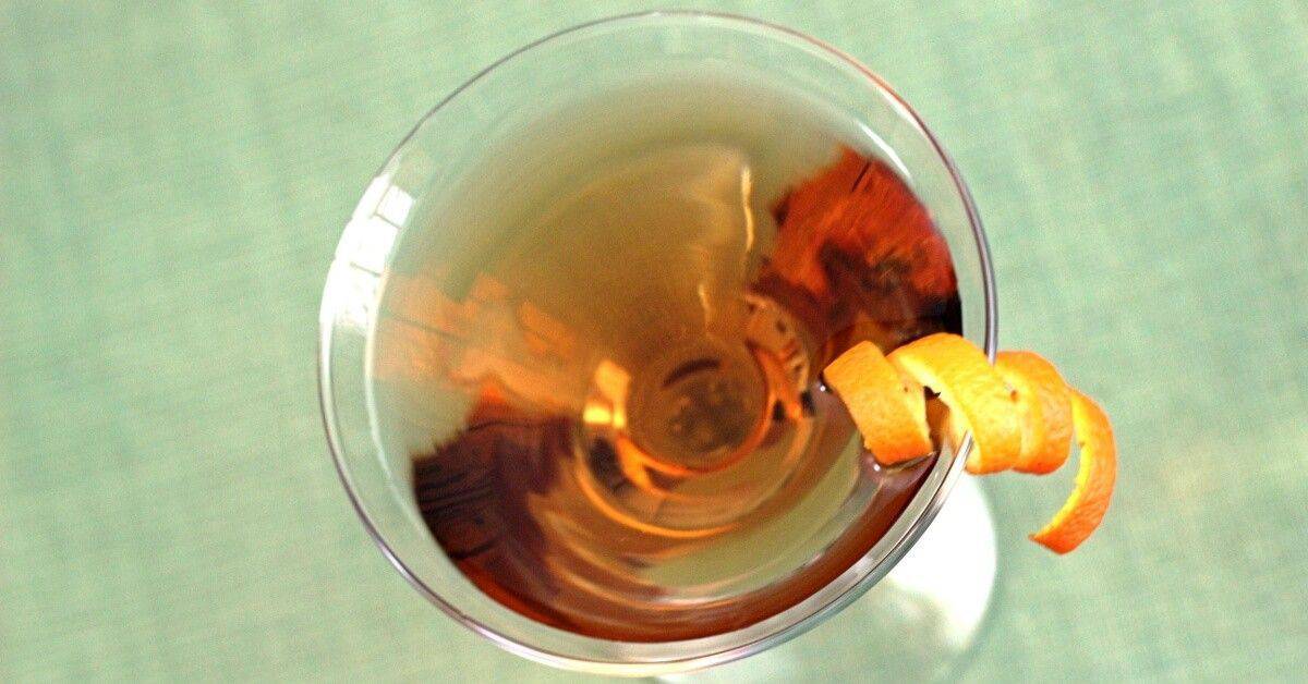 Overhead view of Fox River Cocktail with orange twist against light green background