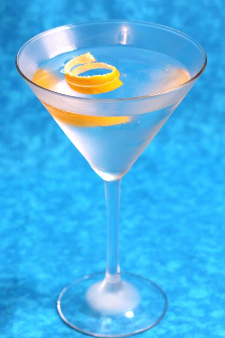 Gin martini with lemon twist against blue background