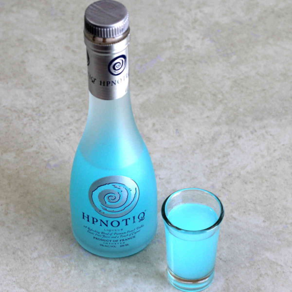 Algled view of Hpnotiq bottle next to shot glass of same