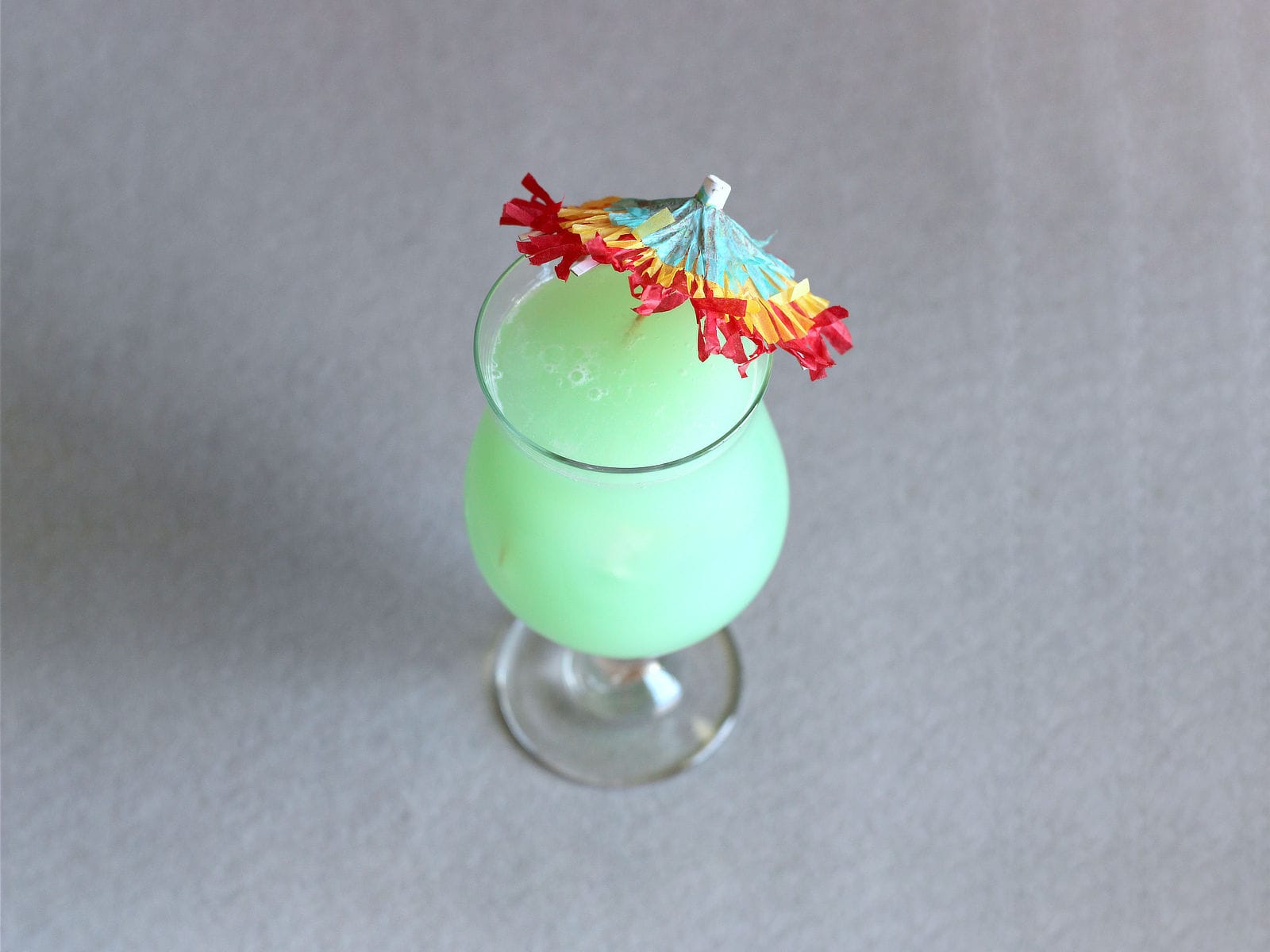 Greenish Hpnotiq Breeze cocktail with umbrella
