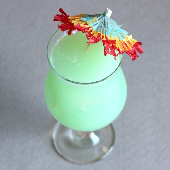 Greenish Hpnotiq Breeze cocktail with umbrella