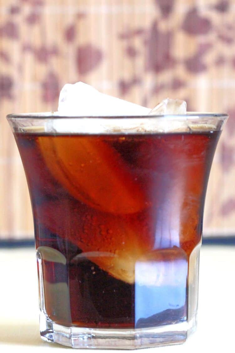 Jack and Coke drink on table in front of patterned background