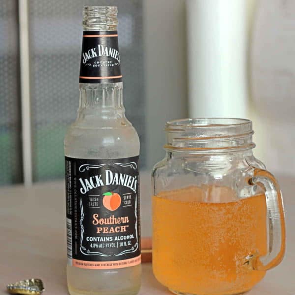 Empty Jack Daniels Southern Peach bottle next to glass of poured beer