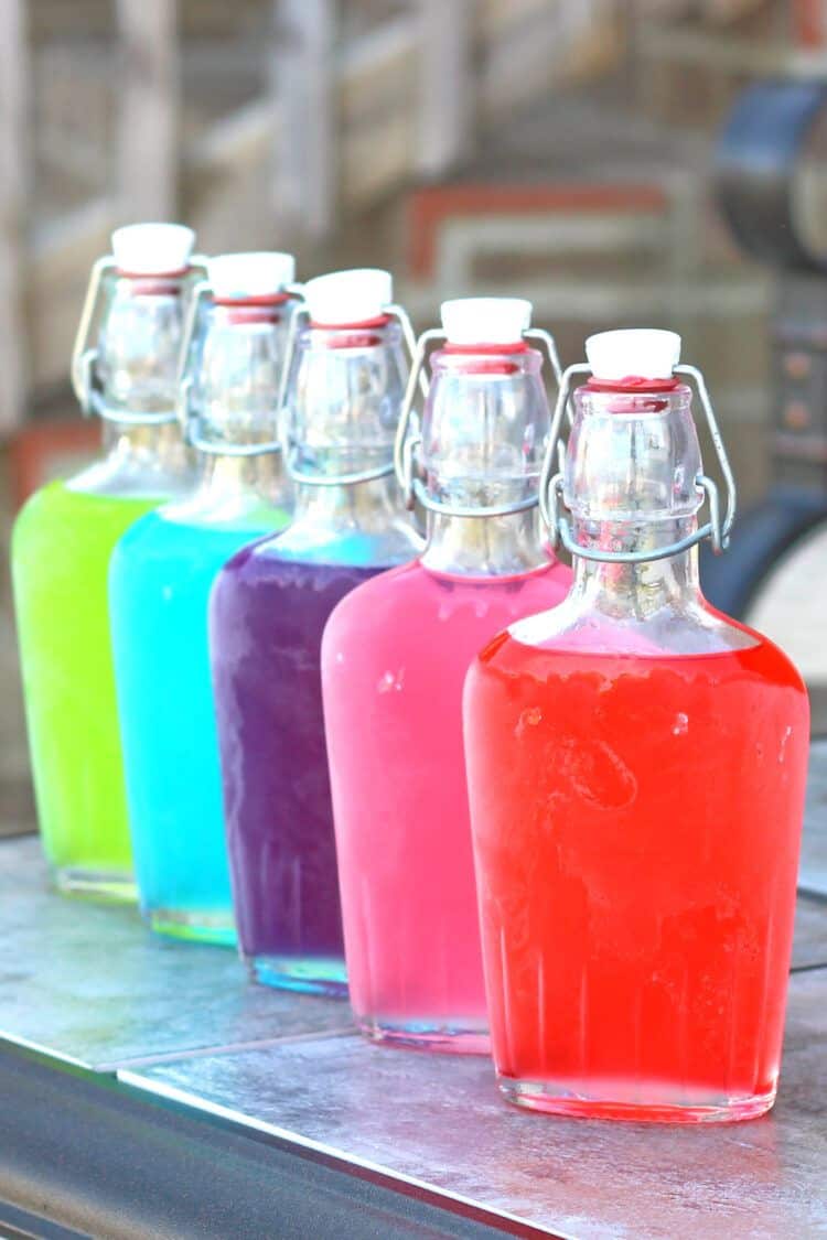 Different angle on Jolly Rancher Vodka chilled in frosty flasks on patio table