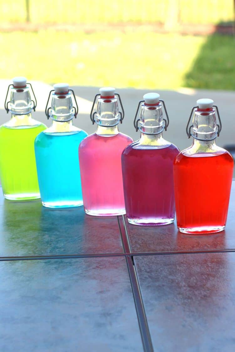 Jolly Rancher Vodka lined up in flasks on a patio table