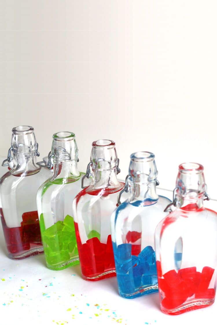 Jolly Rancher candies in flasks with vodka poured over them