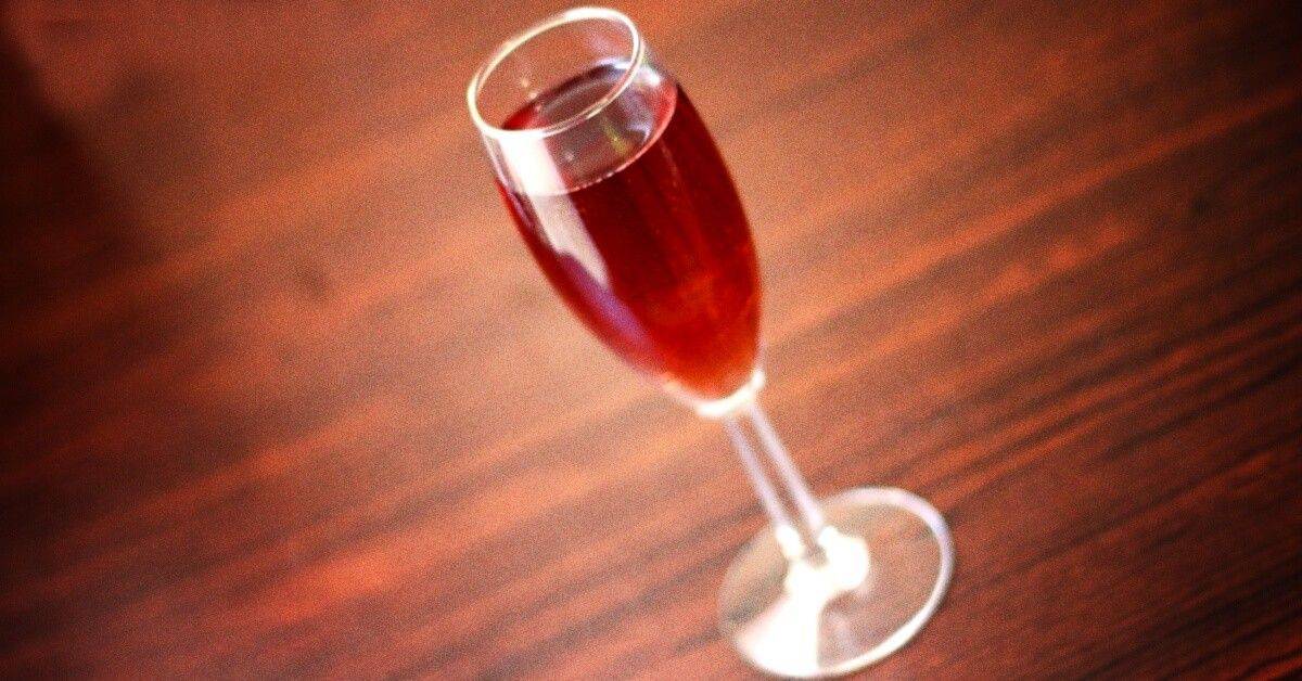 Kir Royale cocktail served in champagne flute on wooden bar top