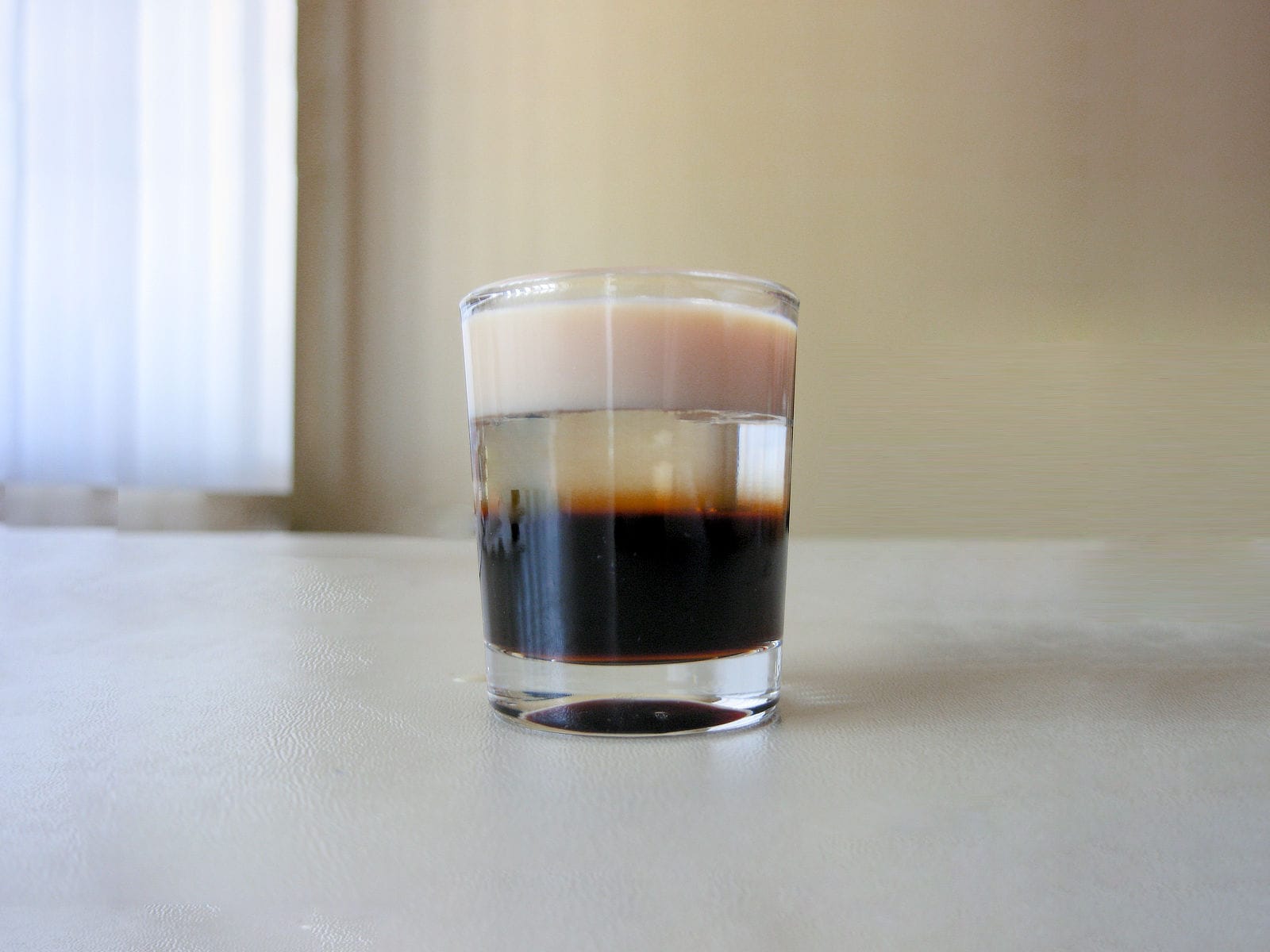 Layered cocktail in glass on table