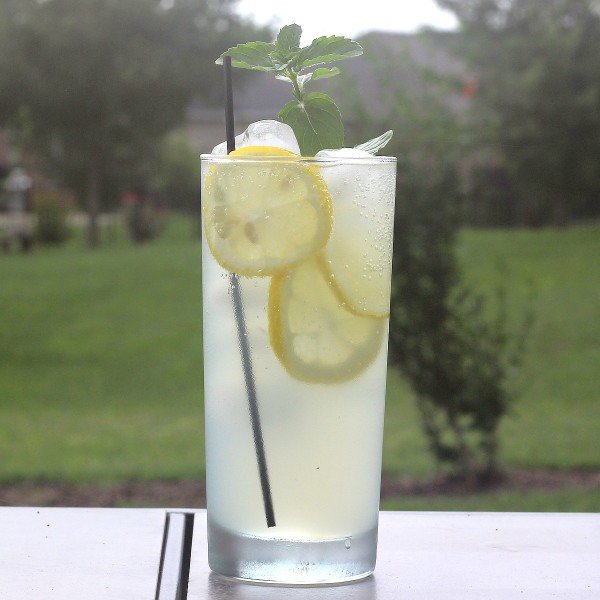 Limoncello Collins drink on patio table with grassy background