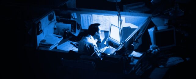 Man Sits At Office Desk Alone At Night