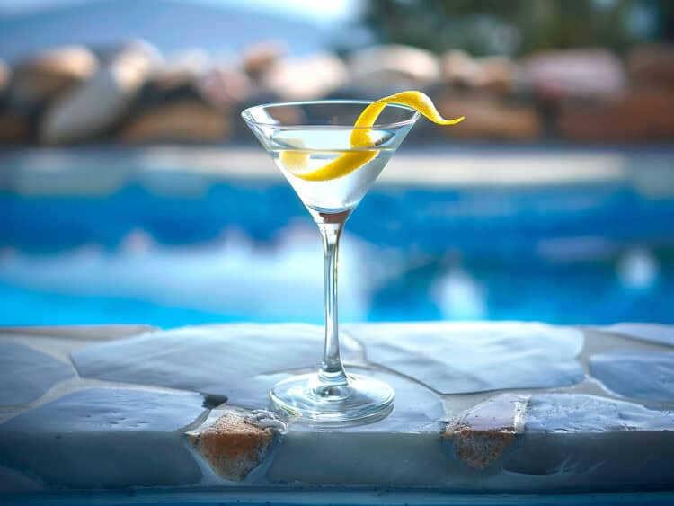 Martini with a lemon twist by a pool