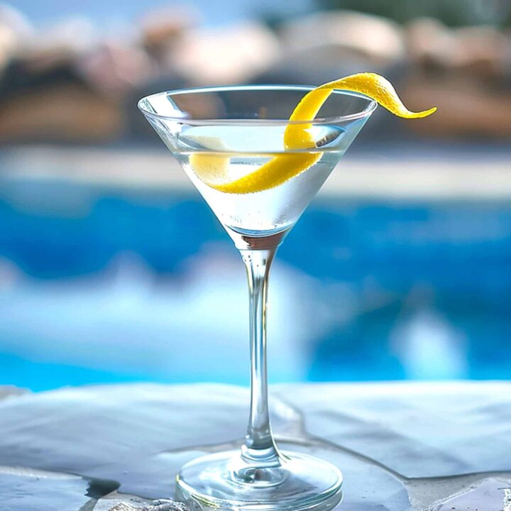 Martini with a lemon twist by a pool