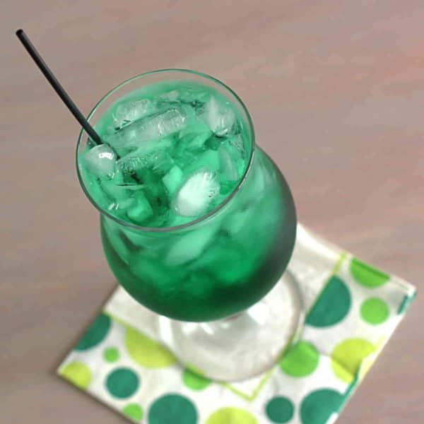 Tilted view of deep green Misty Mint cocktail in hurricane glass