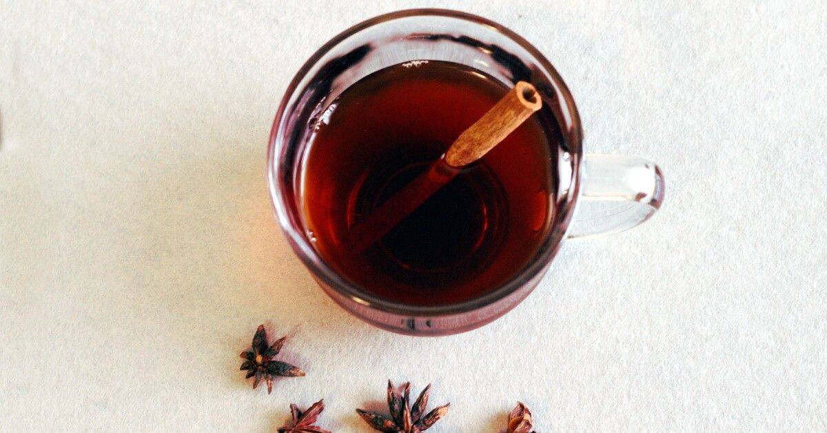 Mulled wine in glass mug with cinnamon stick