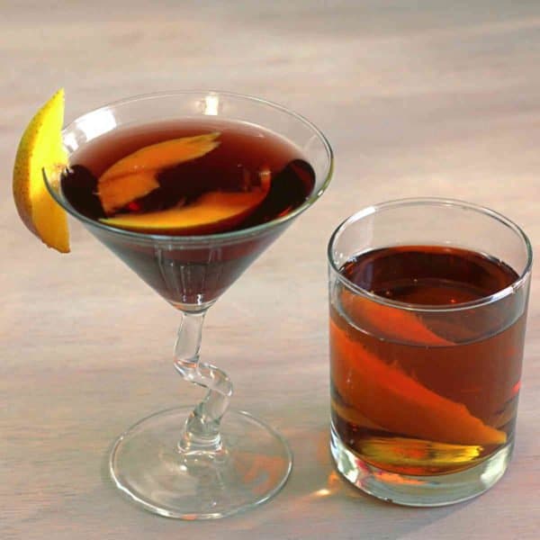 Two drinks on table with fruit garnish