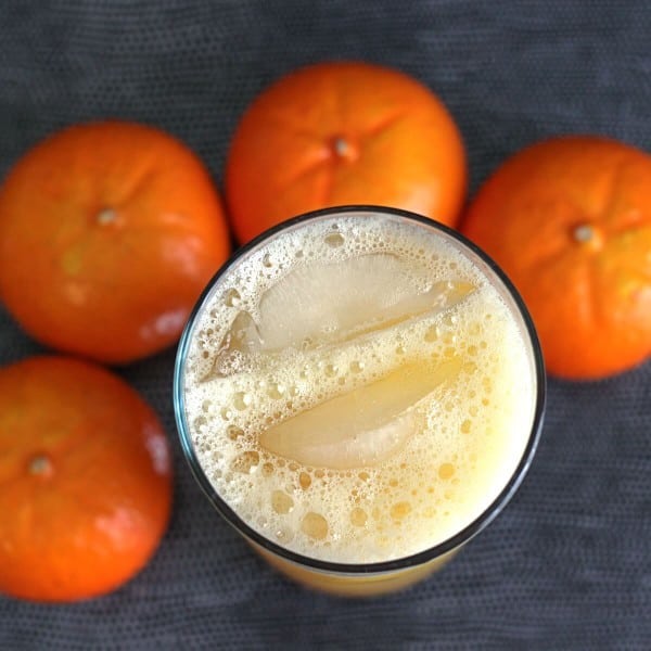 Overhead view of Orange Oasis cocktail in tall glass surrounded by oranges