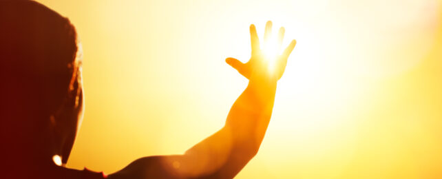 A person reaches for the Sun in the sky.