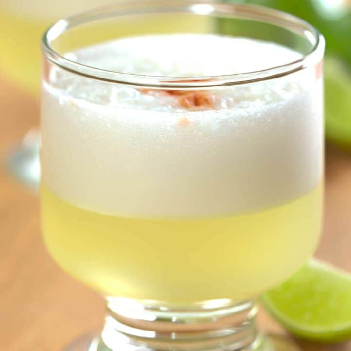 Pisco Sour cocktails on table with lime wedges