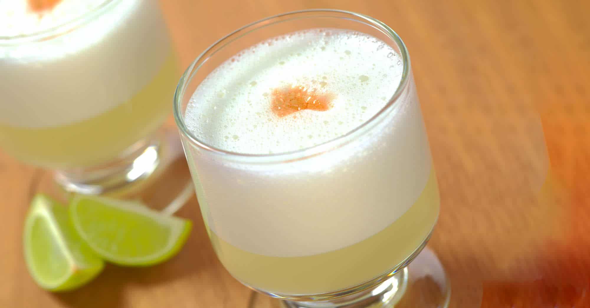 Pisco Sour cocktails on table with lime wedges