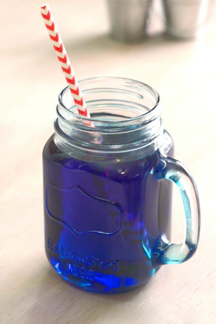 Prison Blues cocktail served in mason jar glass with paper straw