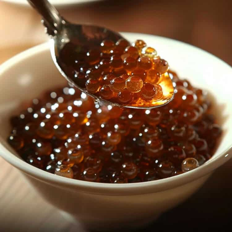 Bowl of rum caviar with a spoonful being held above it