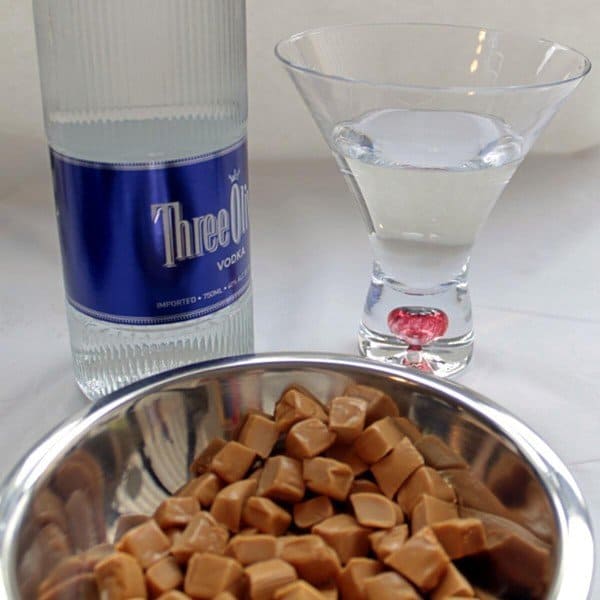 Caramel candies in bowl with glass of vodka