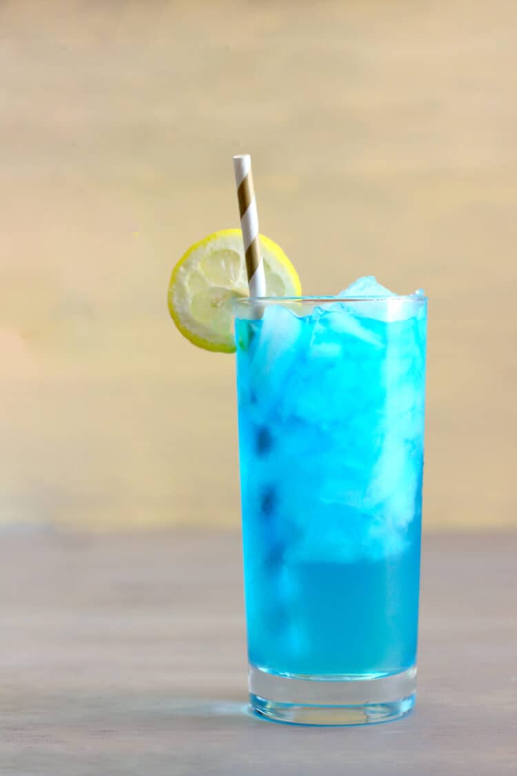 Bright blue Sex in the Driveway drink in a tall glass with lemon and a straw